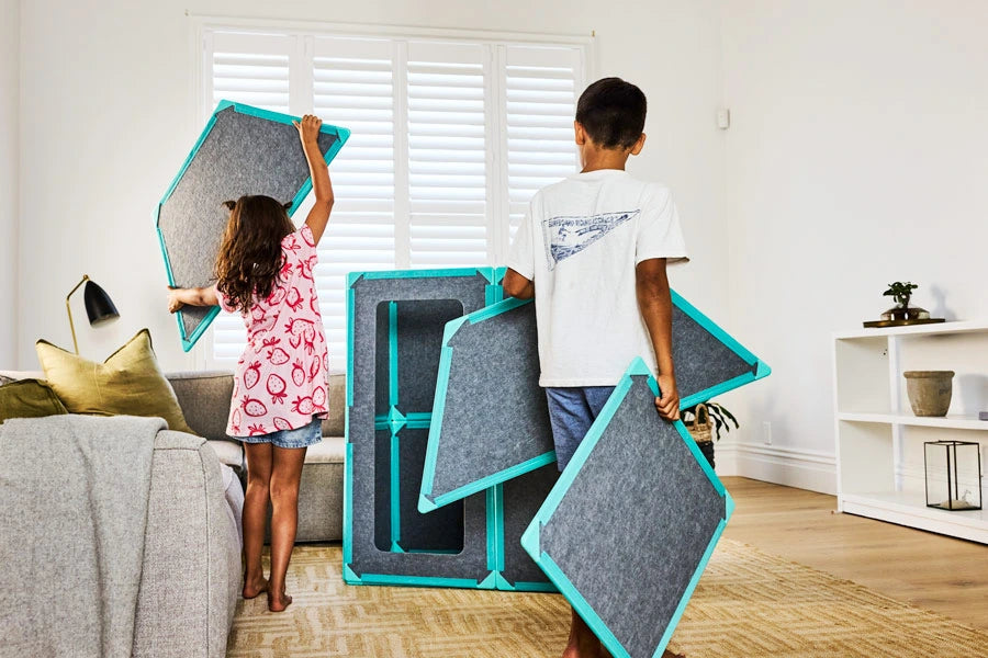 Two children building a life-size magnetic tile house together at home