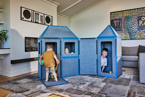 Children playing inside a blue playhouse made from Superspace giant magnetic tiles in a living room
